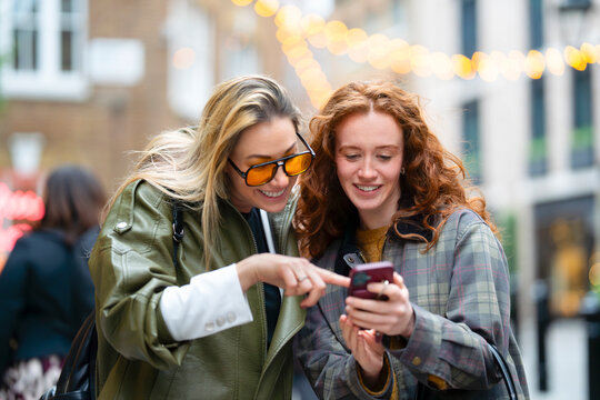 Friends sharing content on smartphone in London