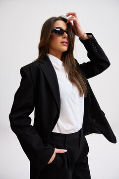 Woman in black suit poses confidently in studio setting