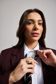 Woman adjusting tie in formal outfit during indoor setting