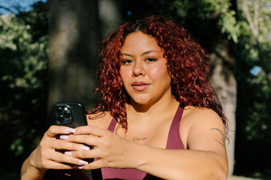 A woman rests after working out in a park checking her smartphone 