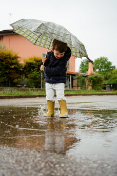A toddler walks outdoors on a rainy day