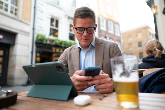 Man multitasking with phone and tablet outdoors