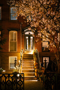 Front entrance of brownstone with lit staircase and cherry blossoms