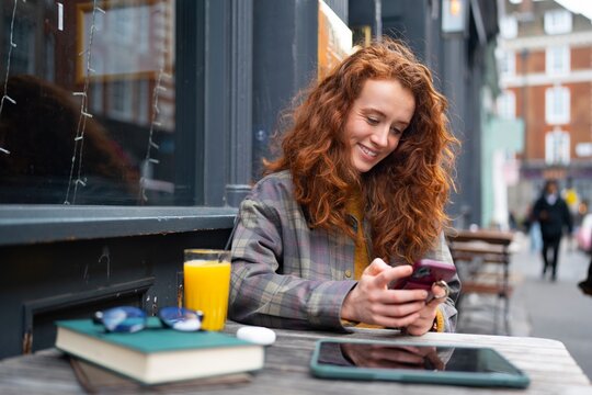 Woman smiling while using phone at cafe