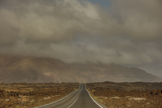 Road stretches through a rocky landscape under cloudy sky