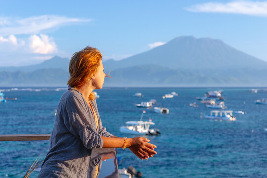 Woman Looking Out Over Tropical Sea with Boats and Mountain View