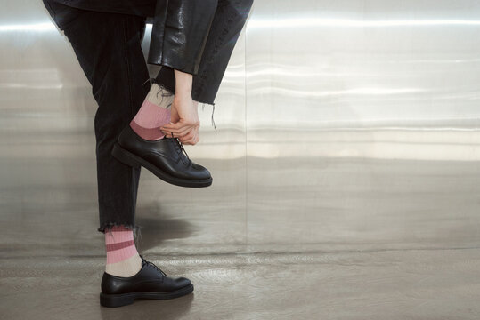 Person adjusts shoes while wearing black shoes and pink socks 