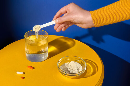 Hand adding powder supplement into water with a measuring scoop