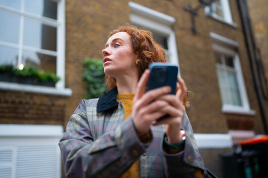 Looking around while holding smartphone in London