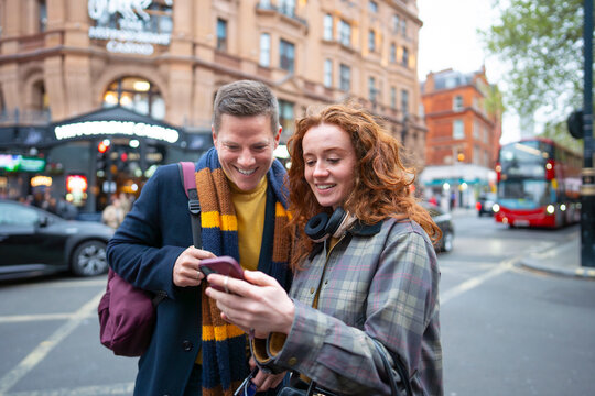 Couple checking smartphone on London street