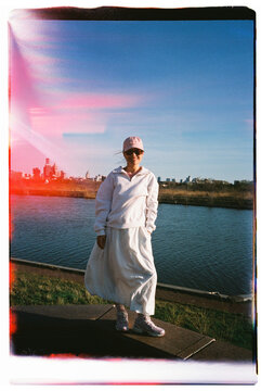 Woman Standing by the River with City Skyline in Background