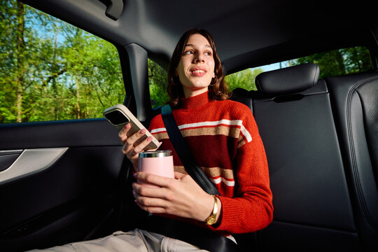 Cheerful woman is commuting in the backseat of a car