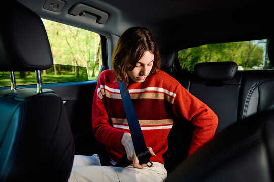Woman fastens seatbelt in the back of a car