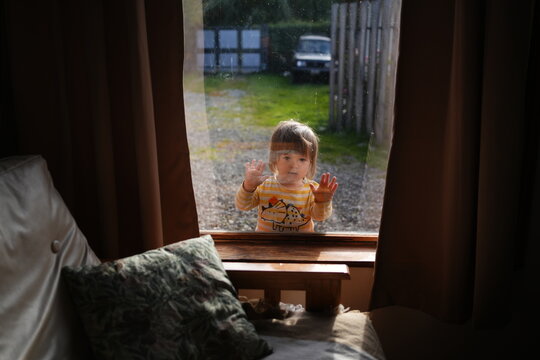 Child Looking Through a Window on a Sunny Day