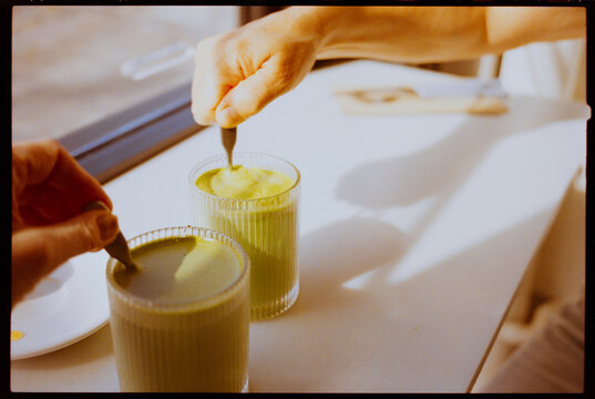 Mixing Matcha Latte at a Table Near the Window