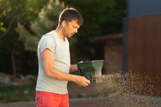 Man Spreading Grass Seed in Backyard