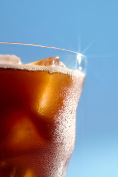 Refreshing iced beverage with condensation on glass on bright blue