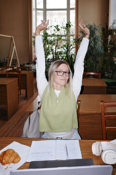 Student stretching in university library during study break