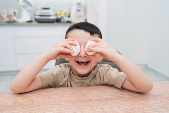 Boy Playing With Eggs Covering Eyes In Kitchen