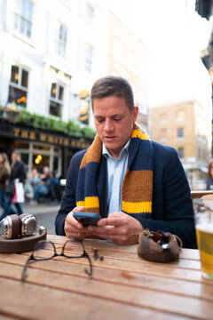 Man checking smartphone at outdoor table