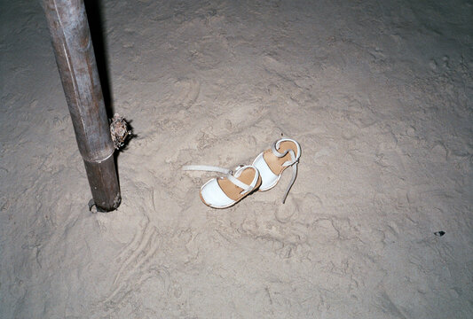 Abandoned White Shoes on Beach Lit by Flash