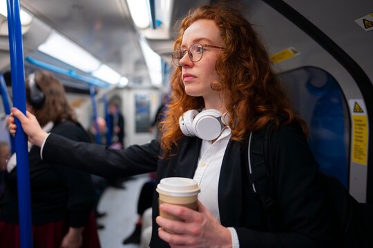 standing in subway holding pole and coffee