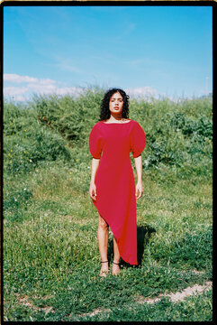 Woman wearing red dress standing in green field