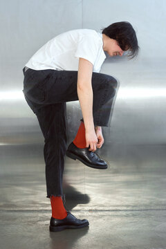 Woman ties her shoelaces on black leather boots