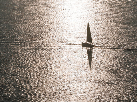 Solitary yacht sailing through open ocean in morning sunshine