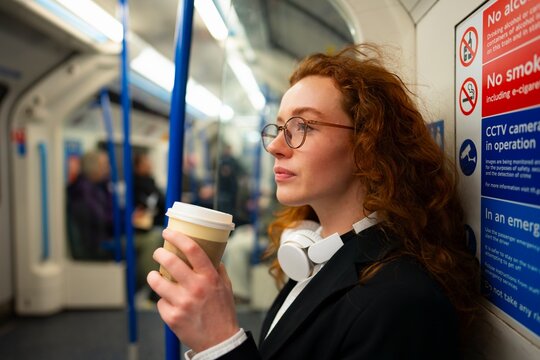 Woman standing inside subway train with coffee