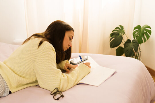 Writing in a notebook while relaxing on a bed in a bedroom