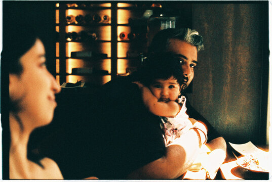 Baby girl resting with parents in low light interior