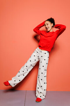 Woman feeling joyful in red sweater and polka dot pants
