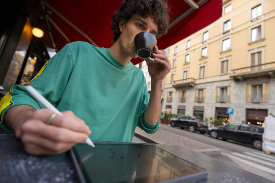 Gen z traveler writes notes while enjoying coffee in Italy