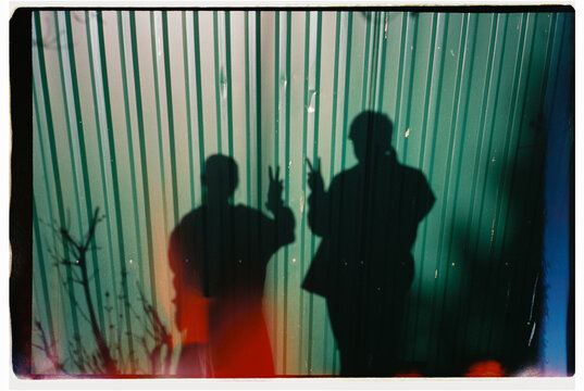 Two People Shadows Showing Peace Signs on Metal Wall