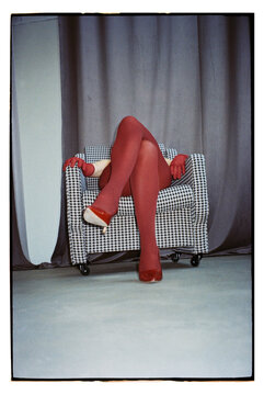 Women's legs in burgundy tights in a chair