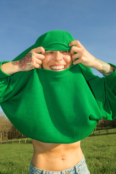 Person shows humor by pulling green hoodie over their head outdoors