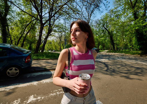 Woman strolls across the street, relishing the sunny day.