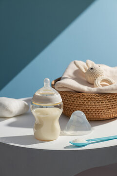 Baby bottle filled with milk and infant formula powder on white table