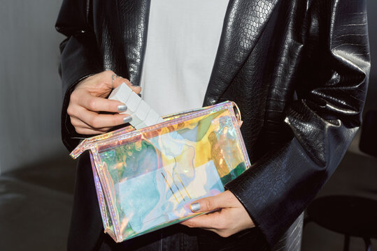 Person placing pill organizer in a iridescent clear bag.