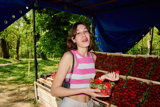 Young woman tries fresh strawberries