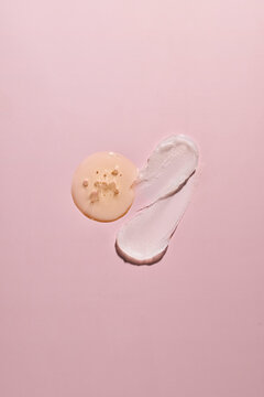 Swatches of cosmetic serum and cream on a pink background