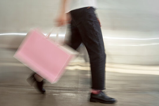 Person carrying a pink bag with motion blur.