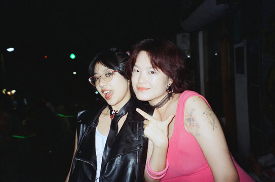 Two Women in Flash Portrait Smiling and Pointing at Night
