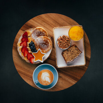 Brunch spread with pancakes, fruit, latte on table