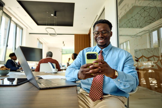 Businessman sits at a desk in a shared office, uses his phone