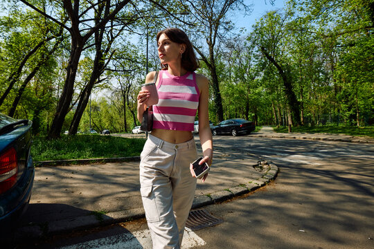 Woman strolls across the street, relishing the sunny day.