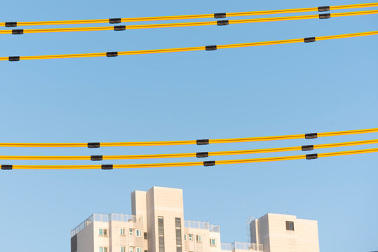 Vibrant yellow electric wires against a clear azure blue sky