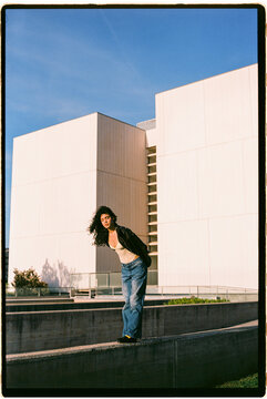 Woman balancing on concrete wall in urban setting
