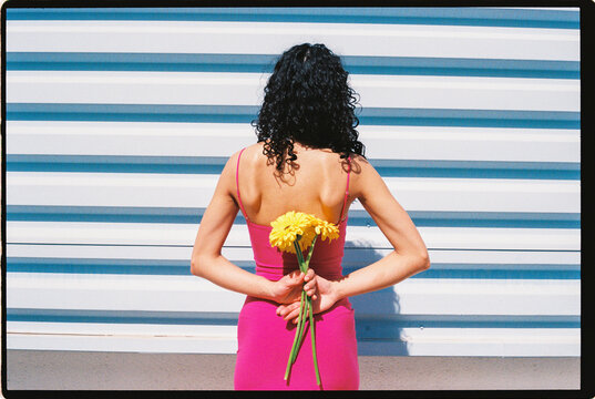 Woman holding yellow flowers behind her back